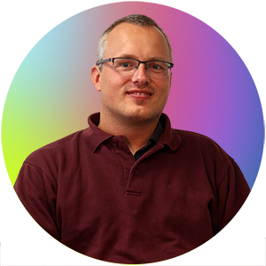 Auf dem Bild ist Herr Markus Looden. Er trägt einen roten Pullover.