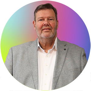 Auf dem Bild ist Herr Jörn Malanowski. Er trägt einen grauen Blazer über einem weißen Hemd.